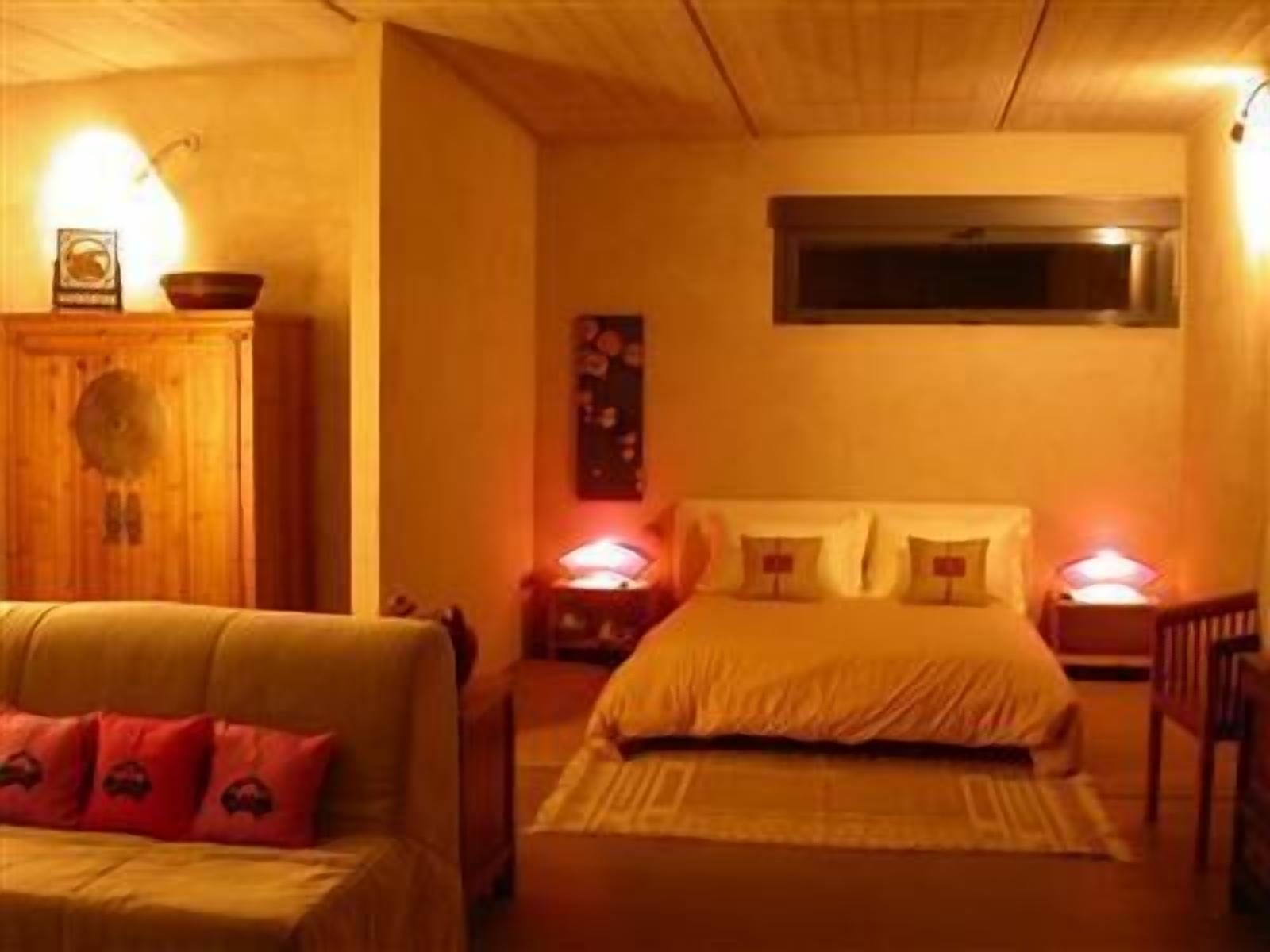 A cozy bedroom with a bed, bedside tables, a wooden wardrobe, and a sofa.