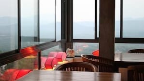 Ein modernes Interieur mit großen Fenstern, einem Holztisch und roten Sitzgelegenheiten.