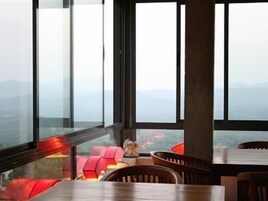 Un interior moderno con ventanas amplias, una mesa de madera y asientos rojos.