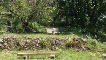 Un parc avec un banc en bois et un mur de pierre.