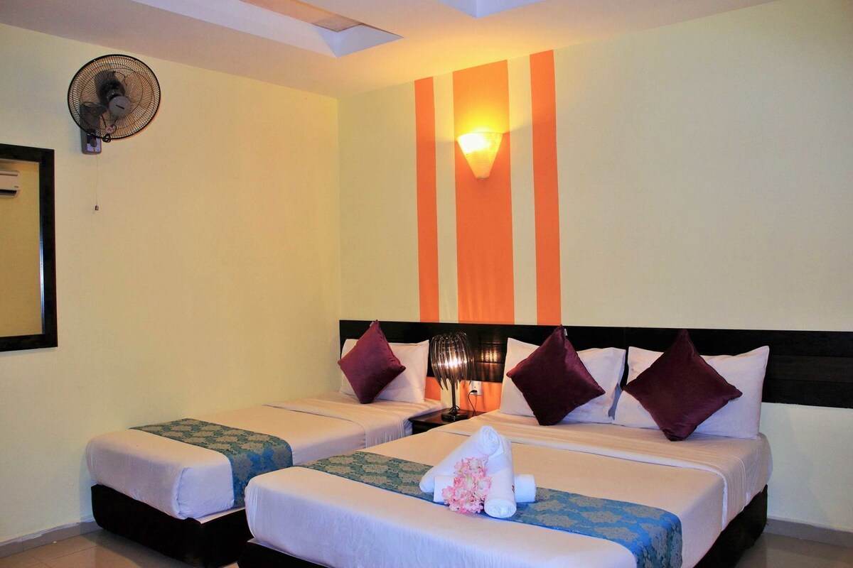A hotel room with two beds, a wall-mounted fan, a wall-mounted light, and a window with a view.