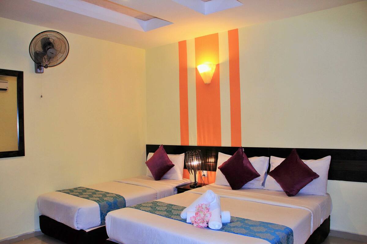 A hotel room with two beds, a ceiling fan, a wall-mounted light fixture, and a mirror on the left wall.