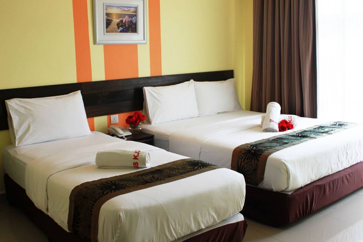 A hotel room with two beds, white bedding, a headboard, a nightstand with a phone, a framed picture on the wall, and a window with curtains.