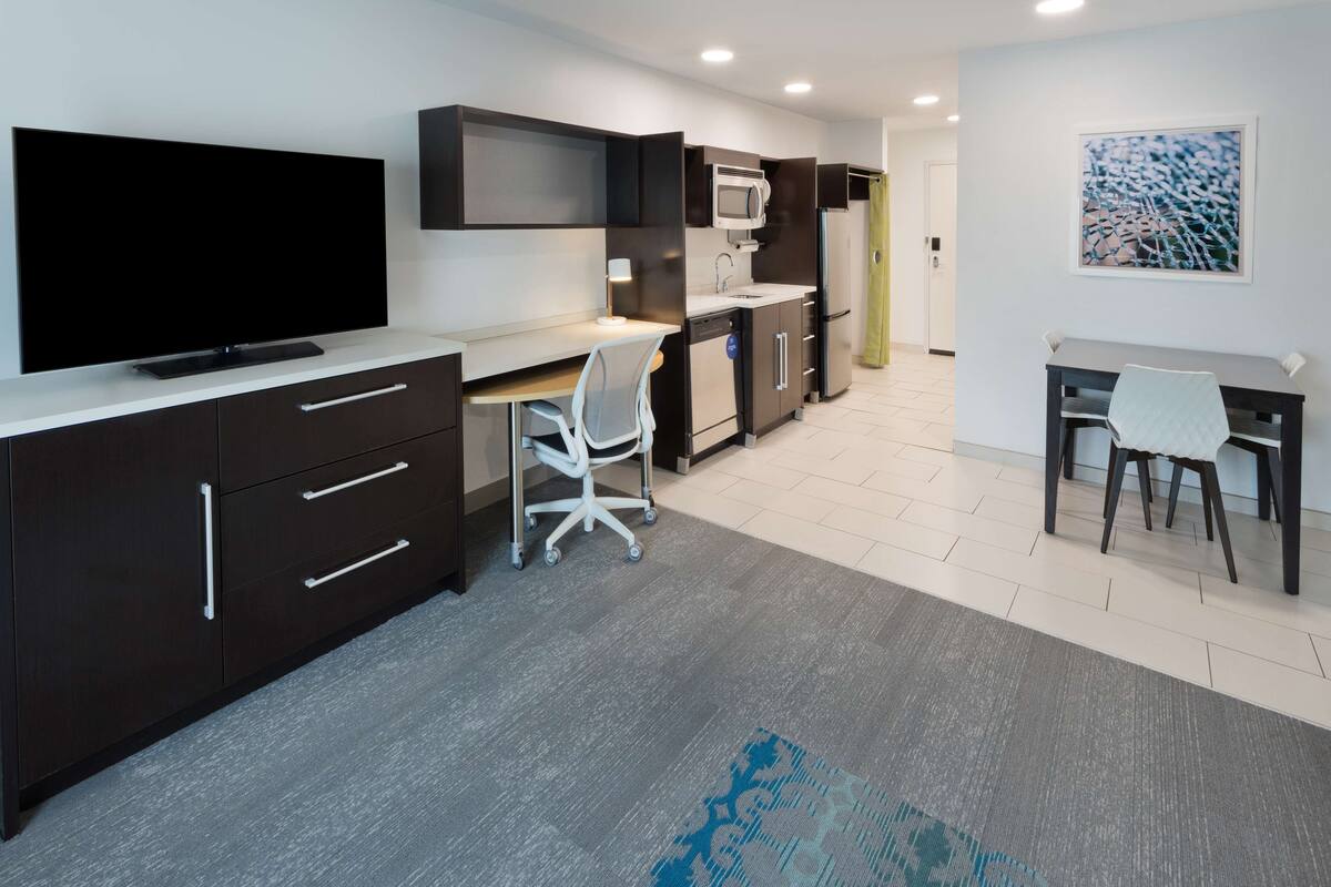 A modern kitchen with a flat-screen TV, a microwave, and a refrigerator.
