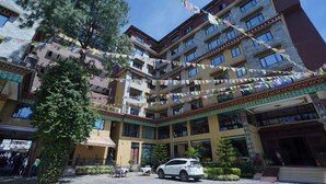 Un edificio de varios pisos con un patio interior, con un coche blanco estacionado al frente.