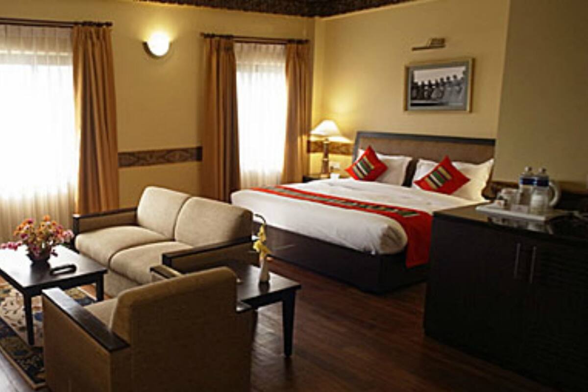 A hotel room with a bed, a sofa, a desk, and a lamp.