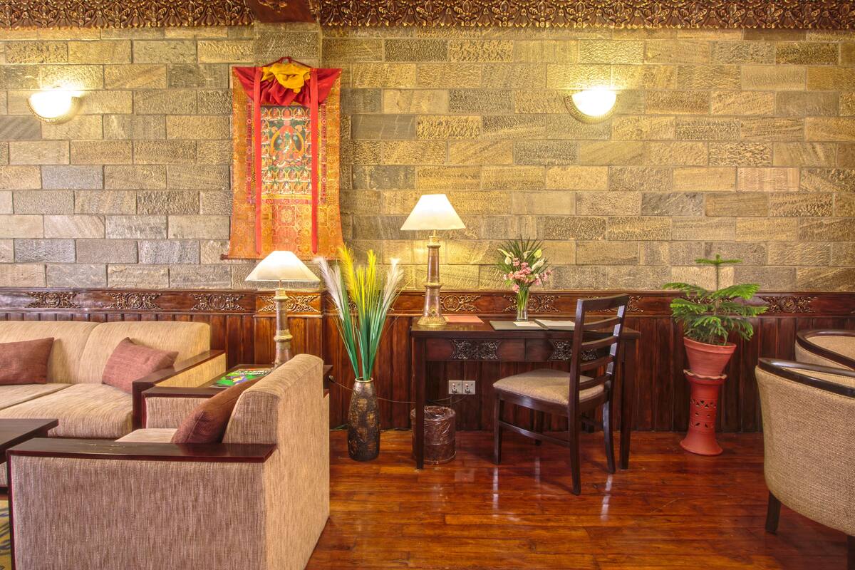 A room with a stone wall, wooden furniture, and a red decorative hanging.