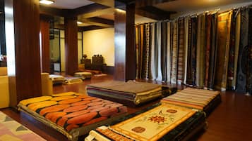 A room with a large collection of textiles, including rugs and carpets, displayed against a wall.