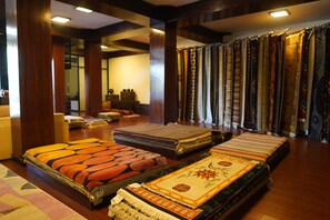 A room with a large collection of textiles, including rugs and carpets, displayed against a wall. - Hotel Tibet International (Kathmandu)
