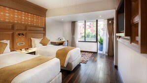 A hotel room with two beds, a desk, a TV, and a window with curtains. - Hotel Tibet (Kathmandu)