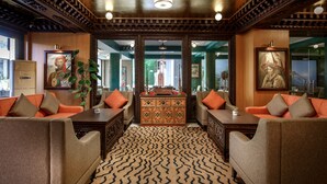A lobby with a patterned carpet, wooden furniture, and decorative mirrors. - Hotel Tibet (Kathmandu)