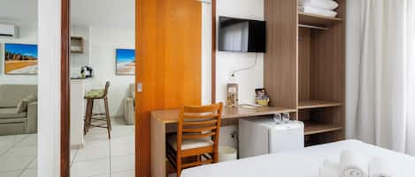 Una habitación de hotel con cama, escritorio, silla, televisor y armario.