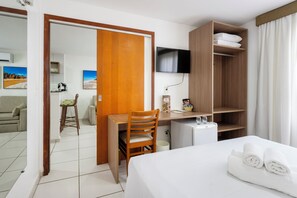 A hotel room with a bed, a desk with a chair, a TV, and a wardrobe. - Villa Park Hotel Natal (Natal)