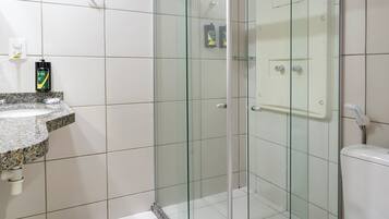 A bathroom with a glass-enclosed shower, a white toilet, and a granite countertop sink.
