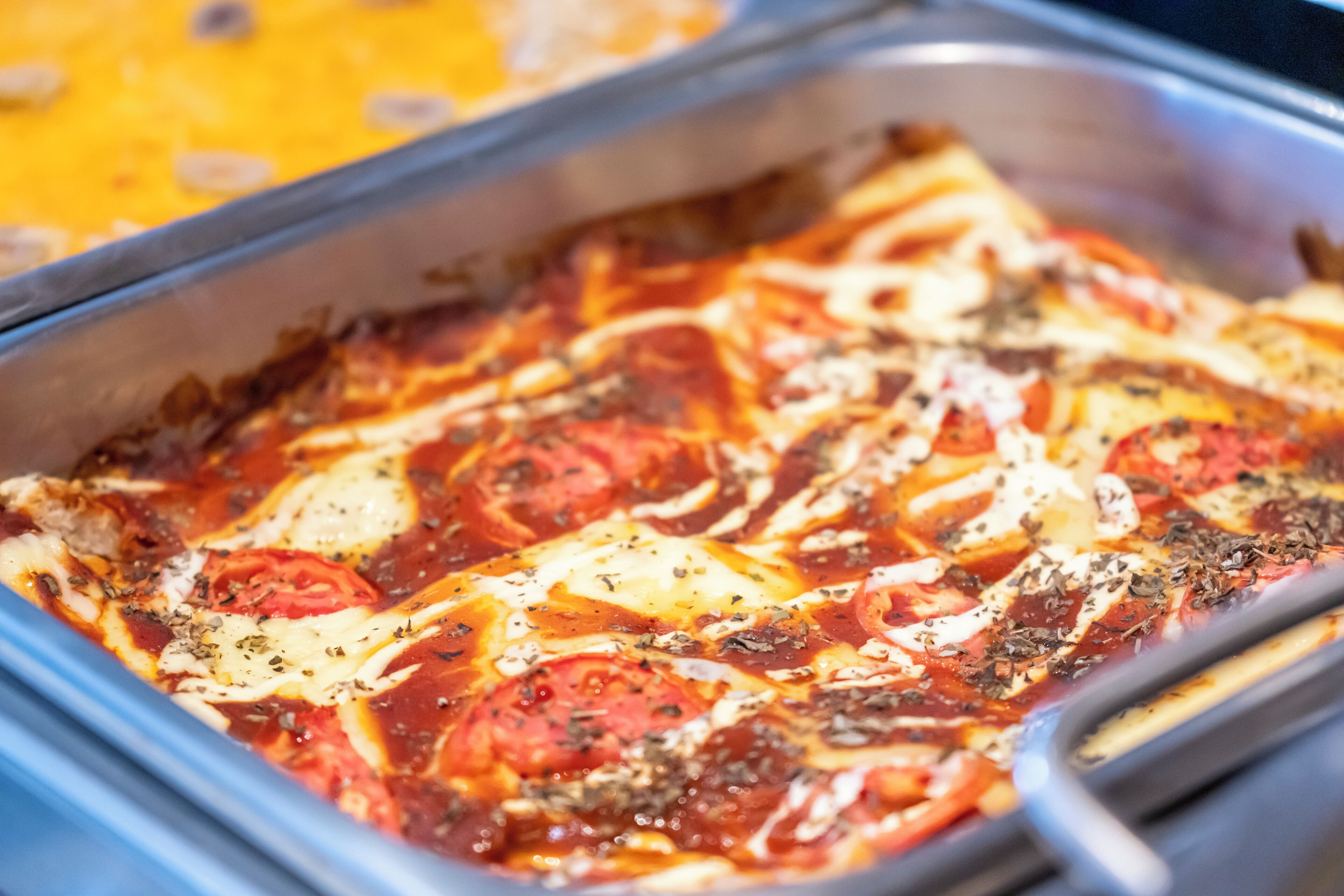 A tray of baked pasta with tomato sauce, cheese, and herbs.