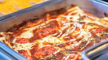 A tray of baked pasta with tomato sauce, cheese, and herbs.