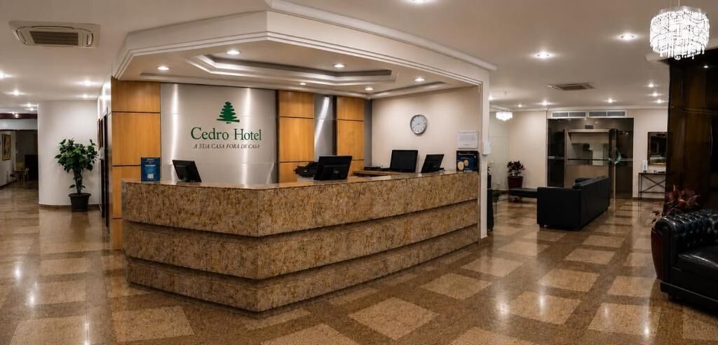 A hotel reception desk with a logo, a clock, and a modern interior design.