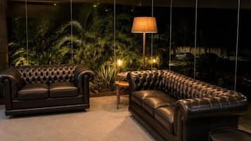 A modern living room with a sofa set, a floor lamp, and a potted plant.
