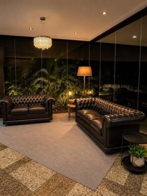 Un salon moderne avec un ensemble de canapés, une lampe sur pied et une plante en pot.