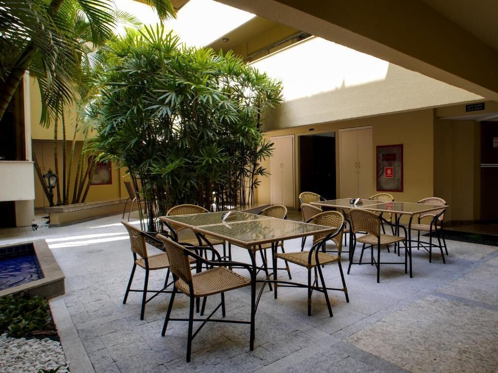Zona d'interior amb terrassa, taules i cadires, envoltada de plantes i una petita piscina.