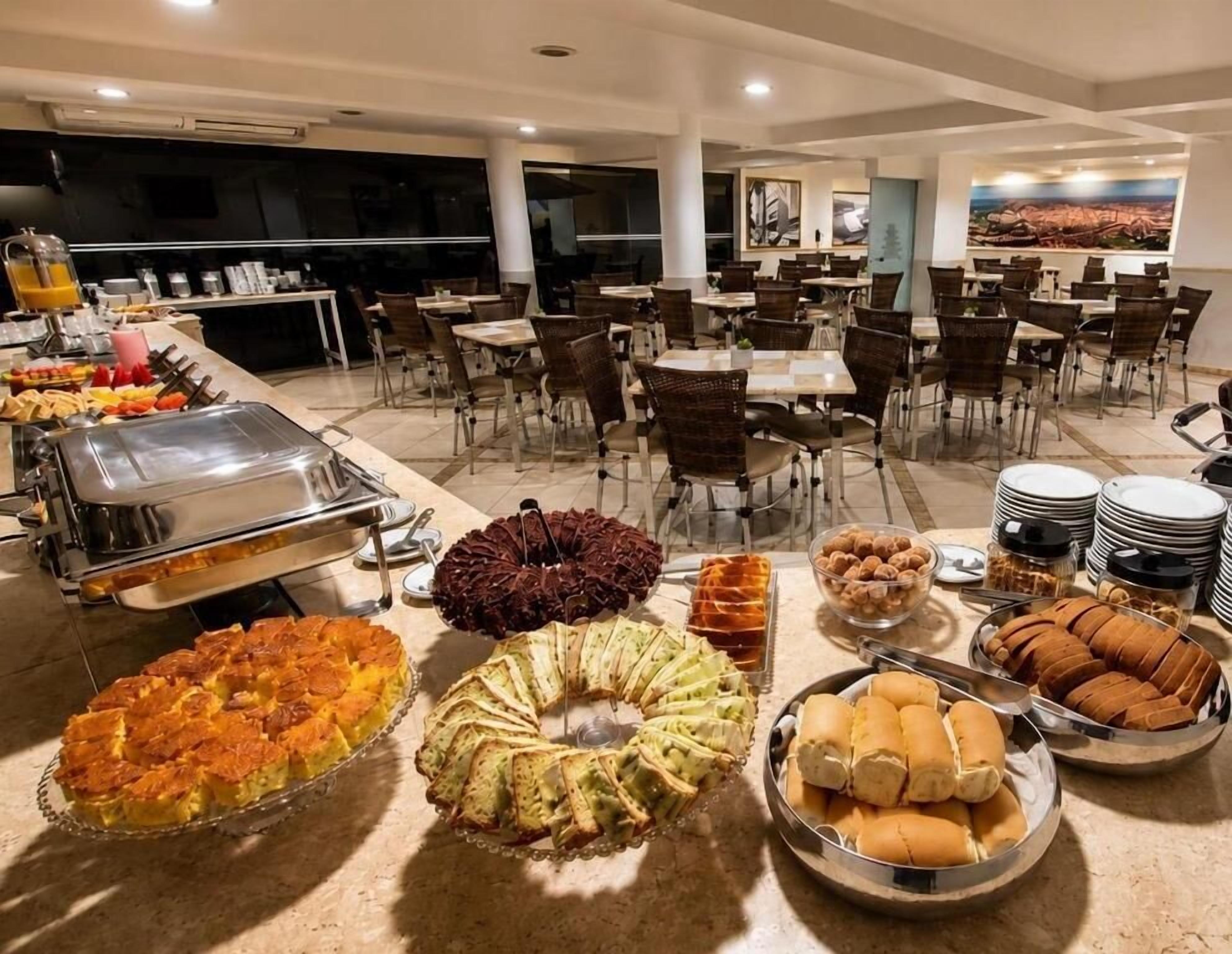 A buffet with various food items and a seating area with tables and chairs.
