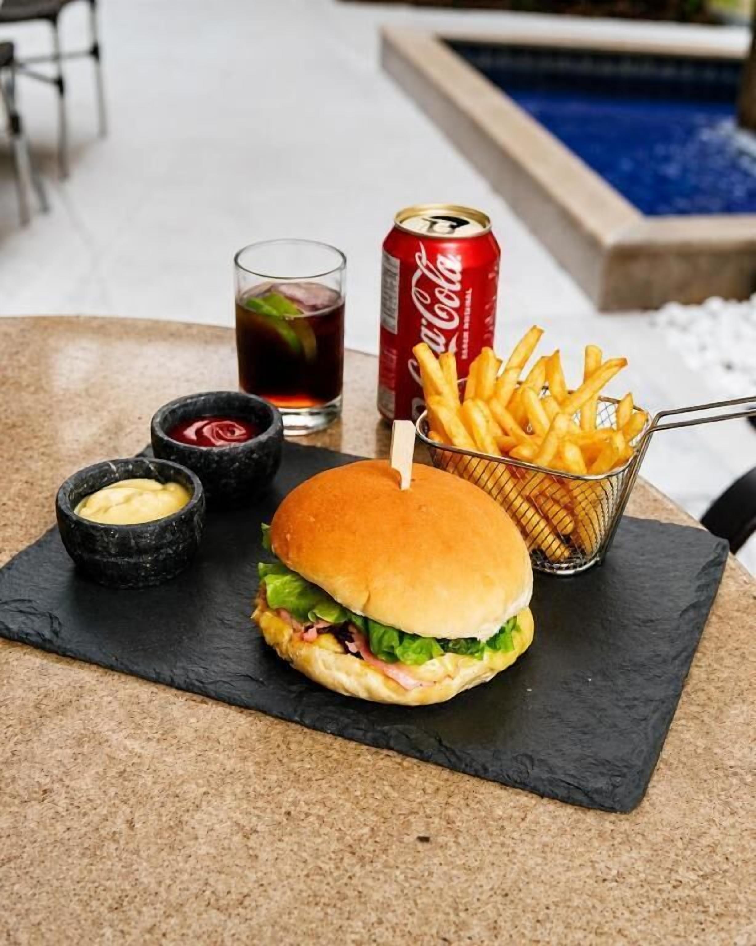 Una hamburguesa con papas fritas y una bebida sobre la mesa.