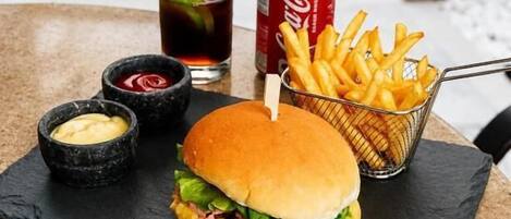 Una hamburguesa con papas fritas y una bebida sobre la mesa.