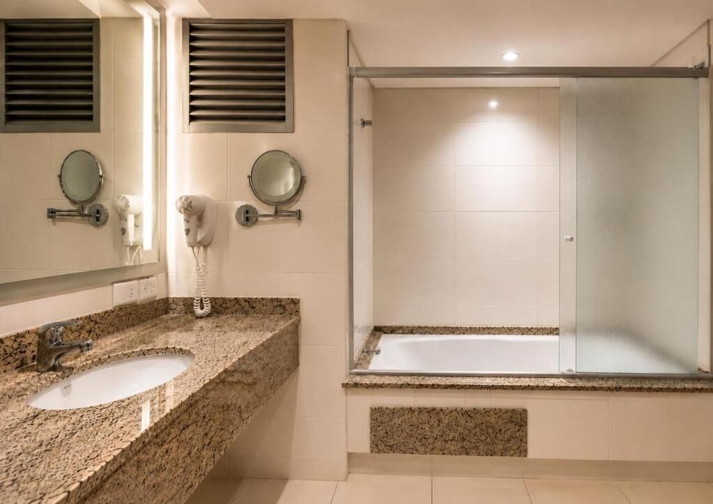 A bathroom with two sinks, a shower, and a mirror.