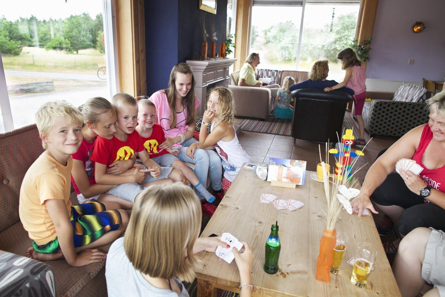 Een groep mensen zit rond een houten tafel in een gebouw met grote ramen.