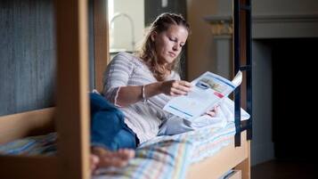 Iemand zit op een stapelbed een boek te lezen.