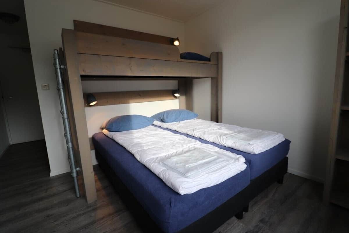 A bunk bed with two beds, each with a blue mattress and white bedding.