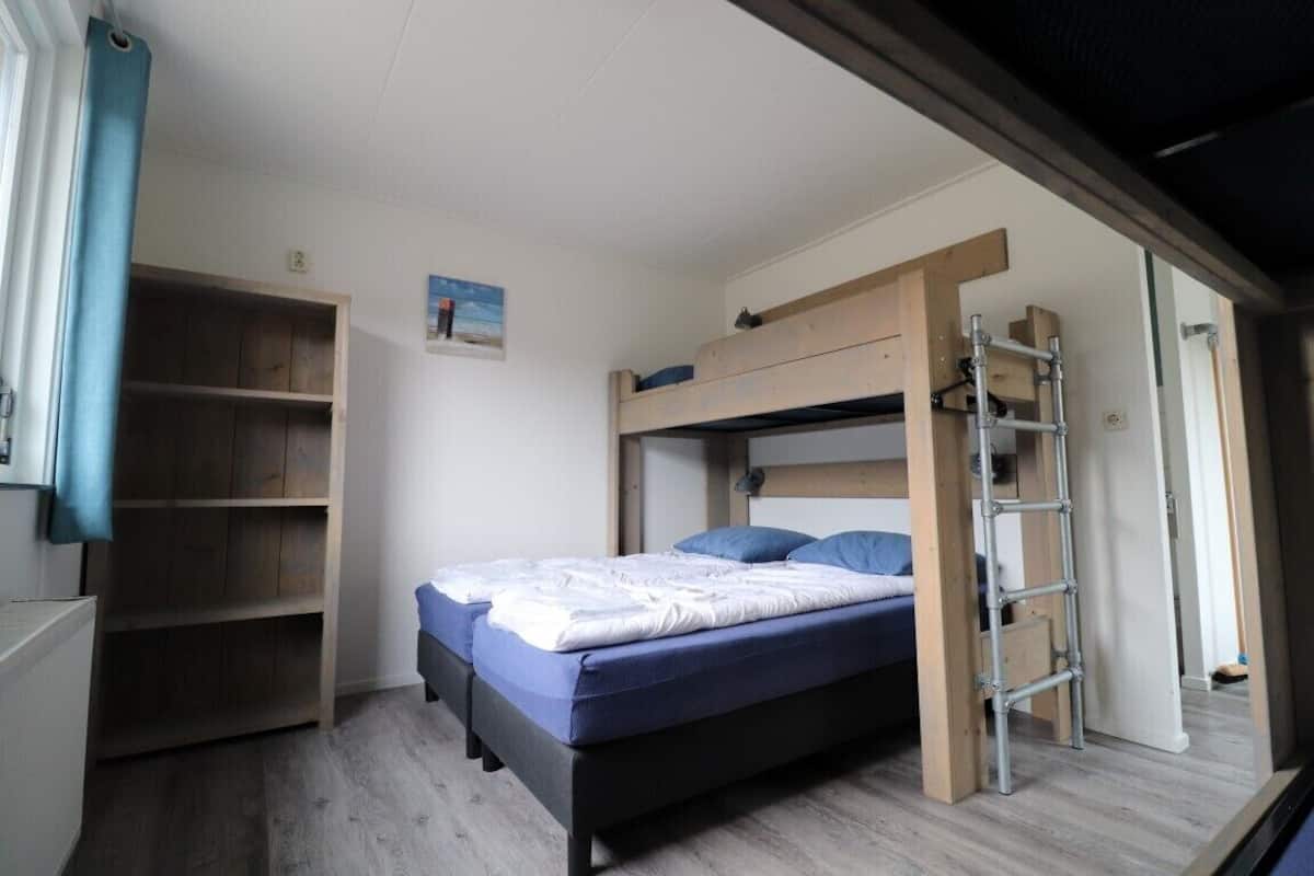 A bedroom with a bunk bed, a ladder, and built-in shelving.