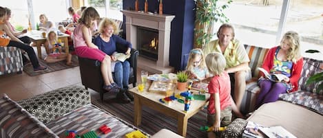 A cozy indoor setting with a fireplace, comfortable seating, and a table with children's toys.