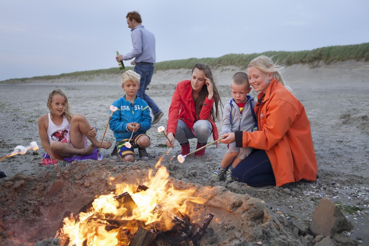 Un groupe de personnes réunies autour d’un feu de camp sur une plage.