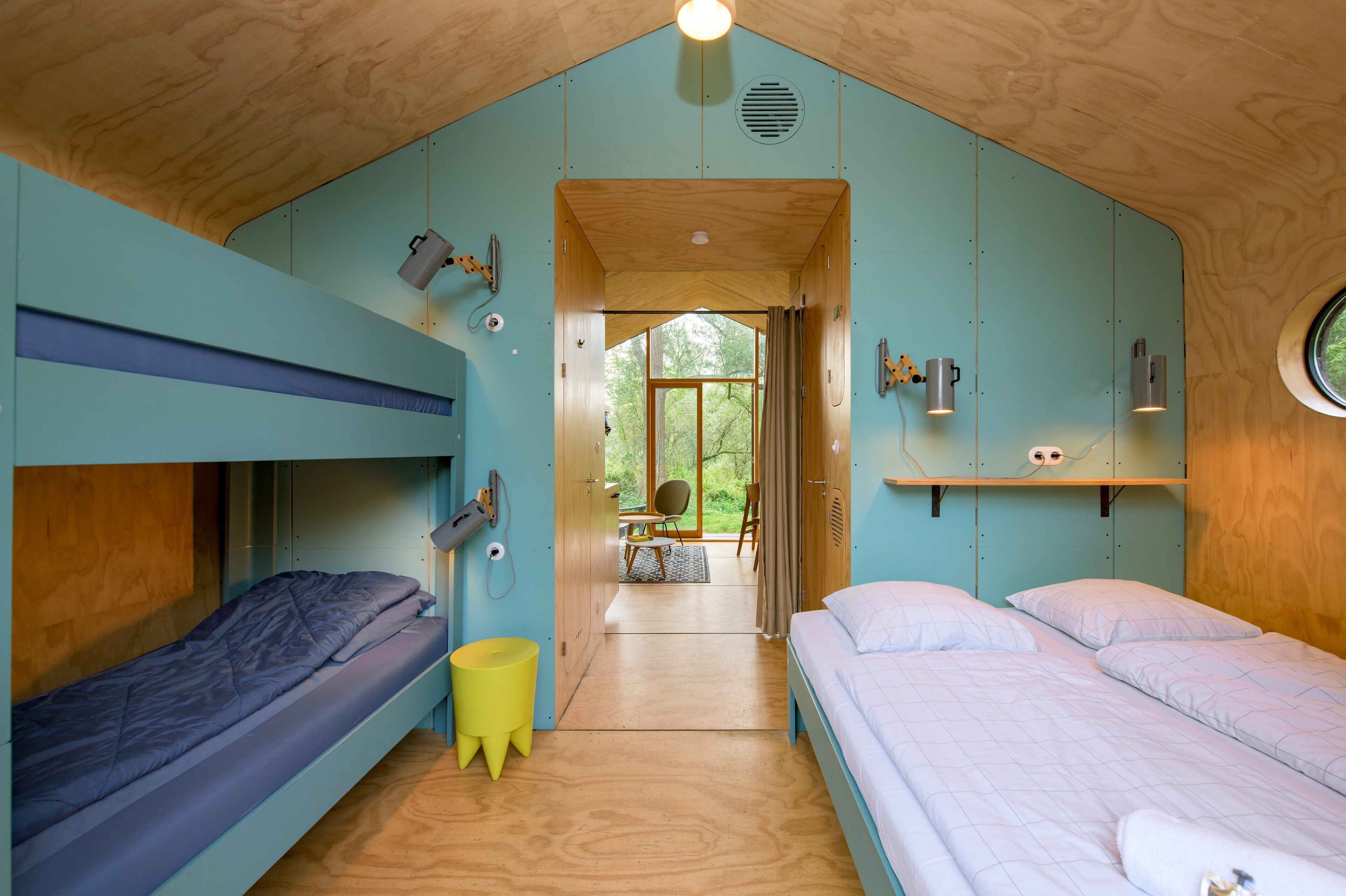 A compact room with bunk beds, a small table, and a view through an open door.