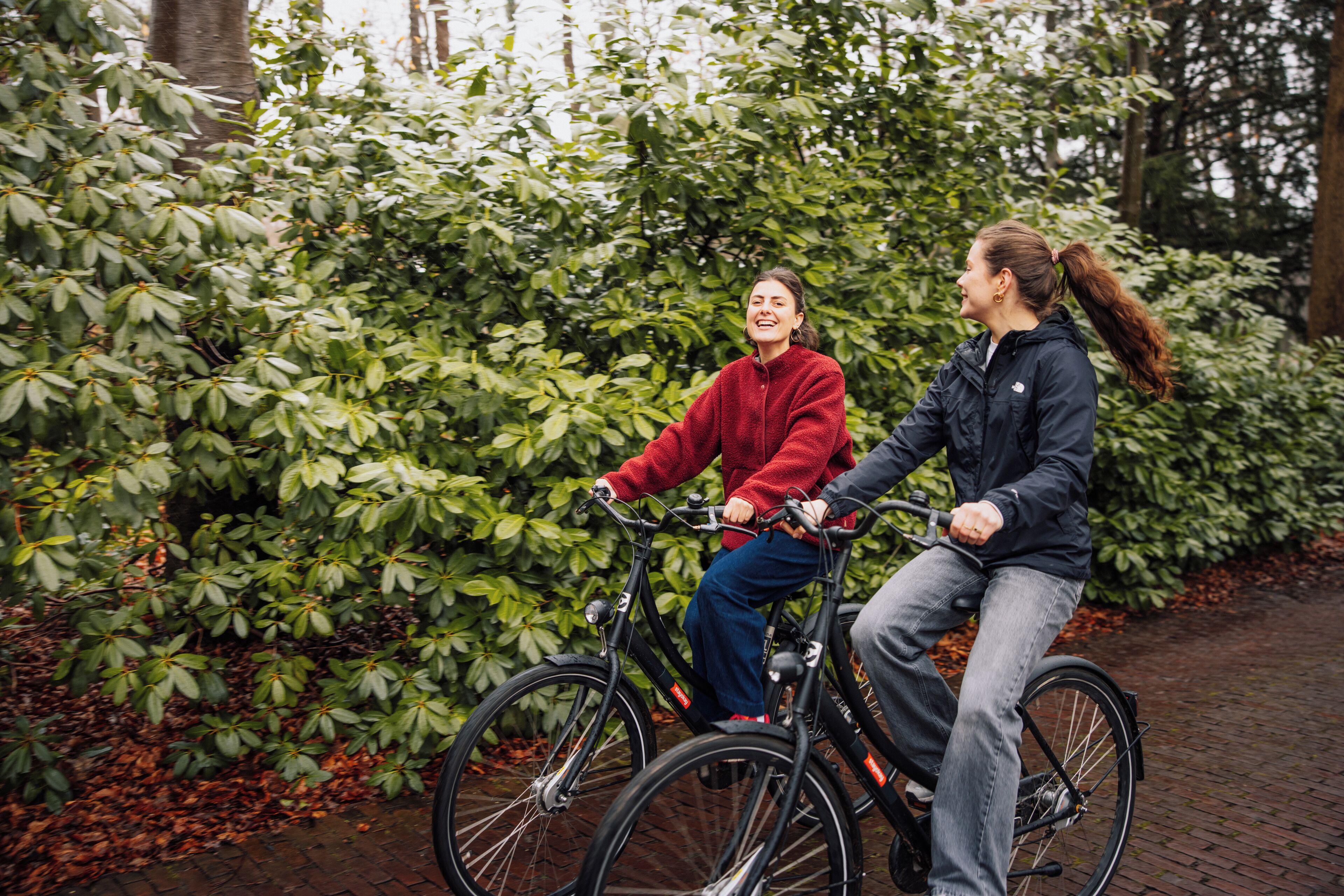 Two individuals on bicycles, surrounded by dense foliage.