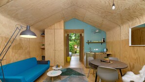 Un intérieur chaleureux, avec des éléments en bois, un canapé bleu, une table à manger et un coin cuisine.
