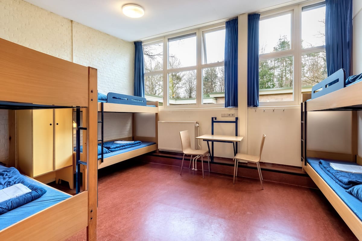 Ein Schlafsaalzimmer mit Etagenbetten, einem Schreibtisch und einem Stuhl.