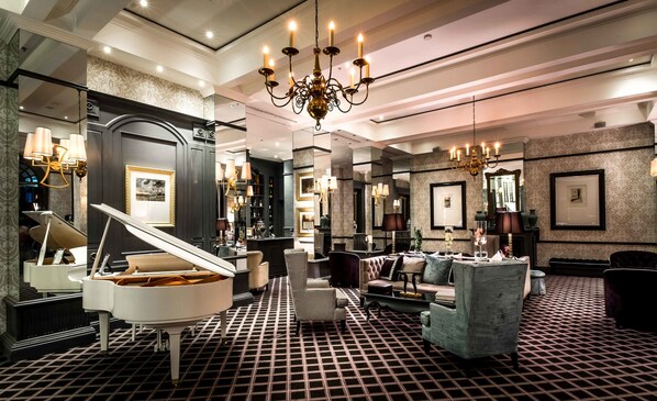A grand room with a grand piano, elegant furniture, and a chandelier.