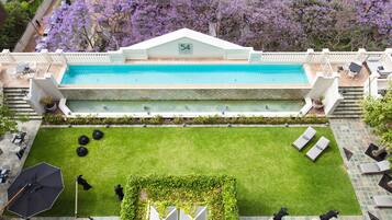 Une piscine sur le toit, agrémentée d’un panneau indiquant le chiffre « 54 », entourée d’une pelouse bien entretenue, de coins salons extérieurs et offrant une vue sur des arbres aux fleurs violettes.