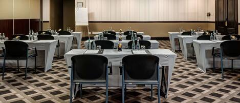 Un salón de conferencias con varias mesas, sillas y una pizarra.