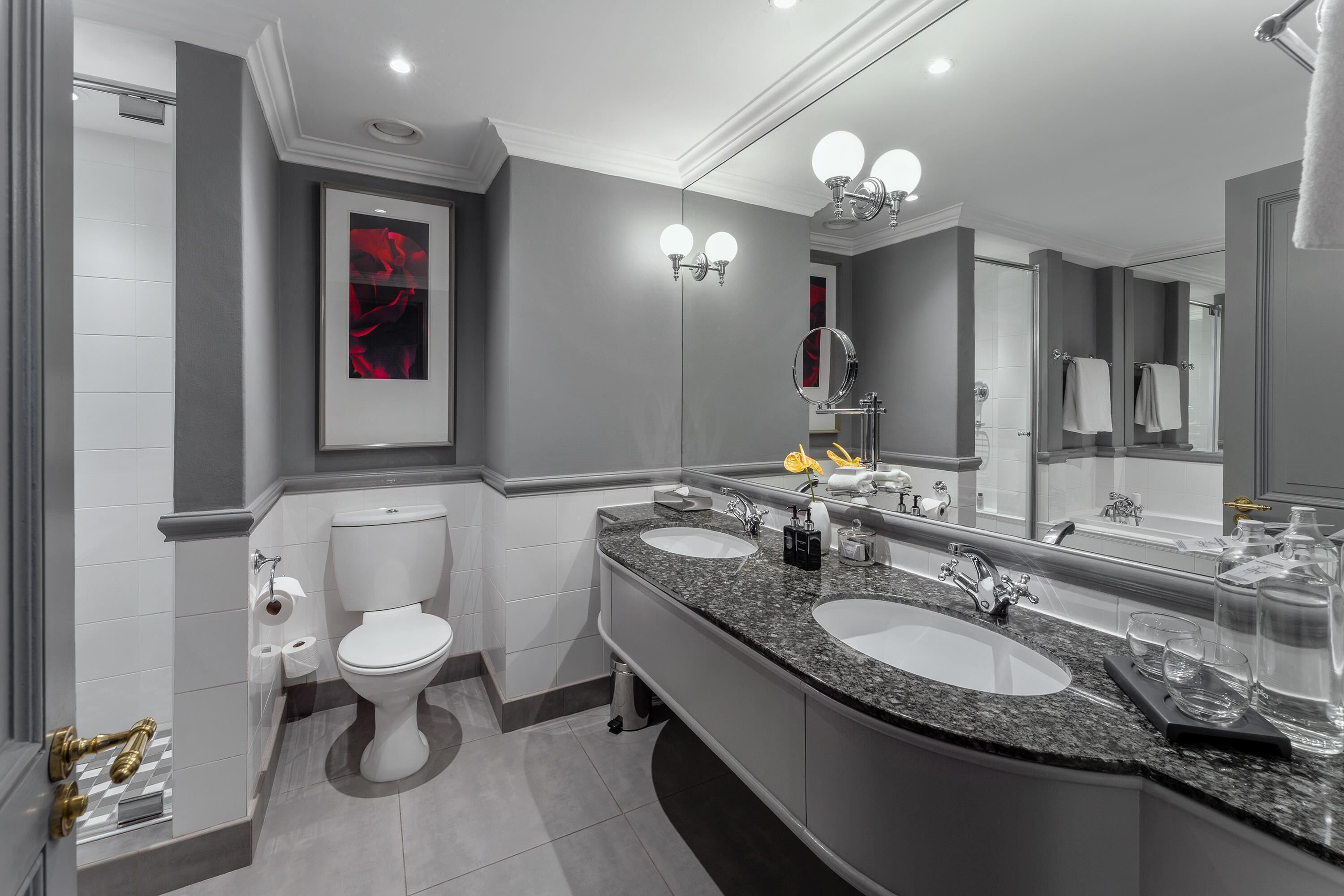 A modern bathroom with two sinks, a toilet, and a large mirror.