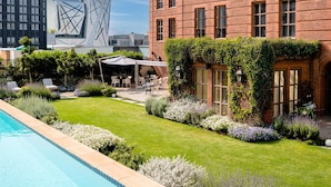 A hotel with a swimming pool, a garden with plants and flowers, and a brick building with multiple windows. - 54 On Bath (Johannesburg)
