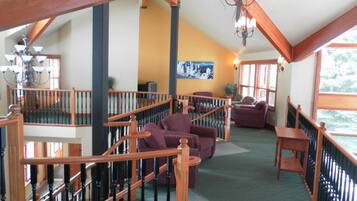 A spacious living area with a wooden staircase, a chandelier, and a large window providing natural light.