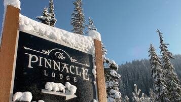 Un senyal de The Pinnacle Lodge envoltat d'arbres coberts de neu.