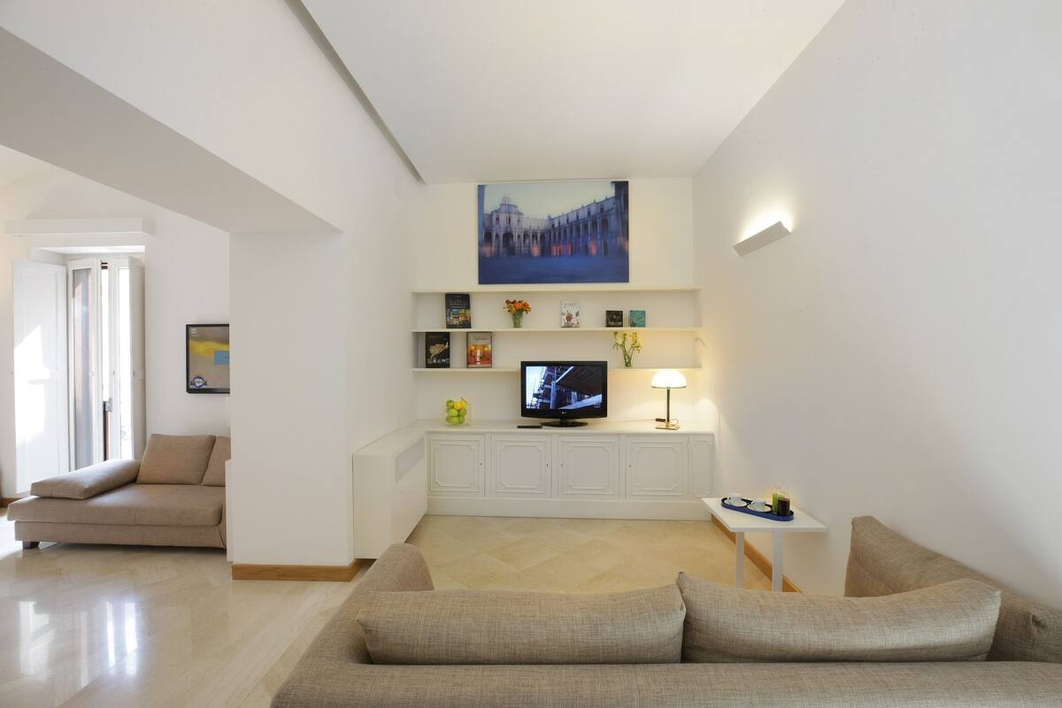 A modern living room with a sofa, a TV, a small table, and a painting on the wall.