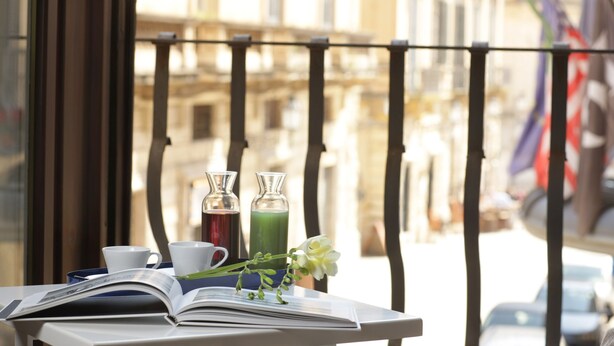 A table with an open book, two cups, two glass bottles with drinks, and a flower. - Santacroce Luxury Rooms (Lecce)