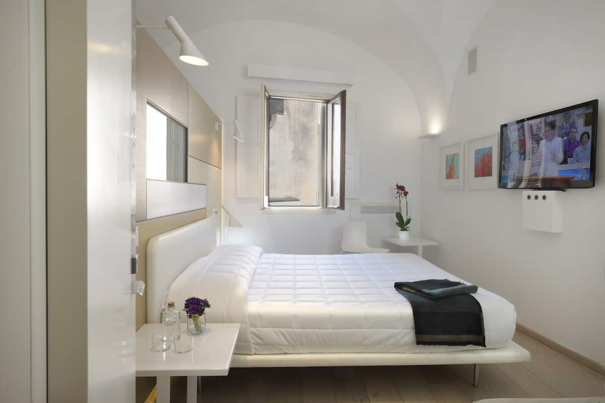 A modern bedroom with a bed, bedside table, and a TV.