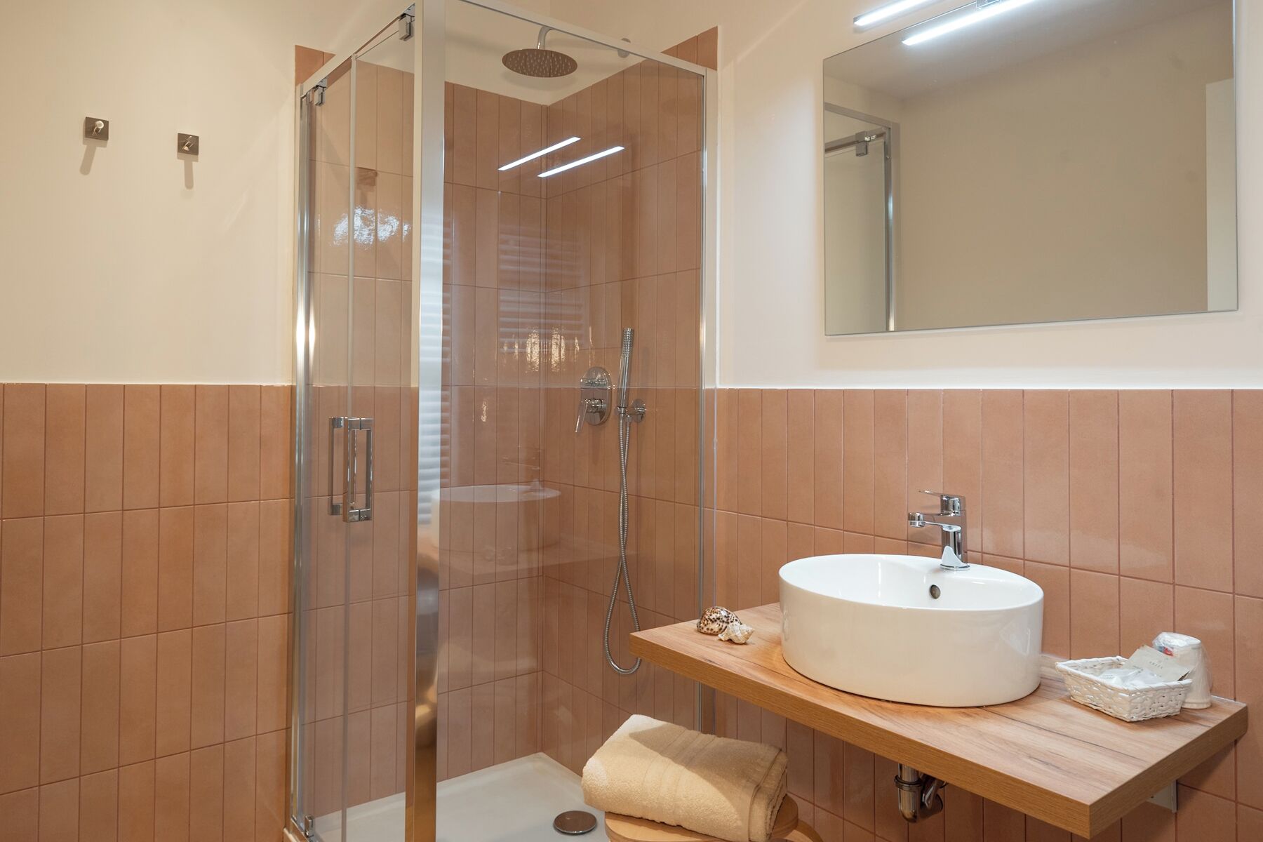 Une salle de bain moderne avec une douche à parois de verre, un lavabo blanc et un meuble-lavabo en bois.