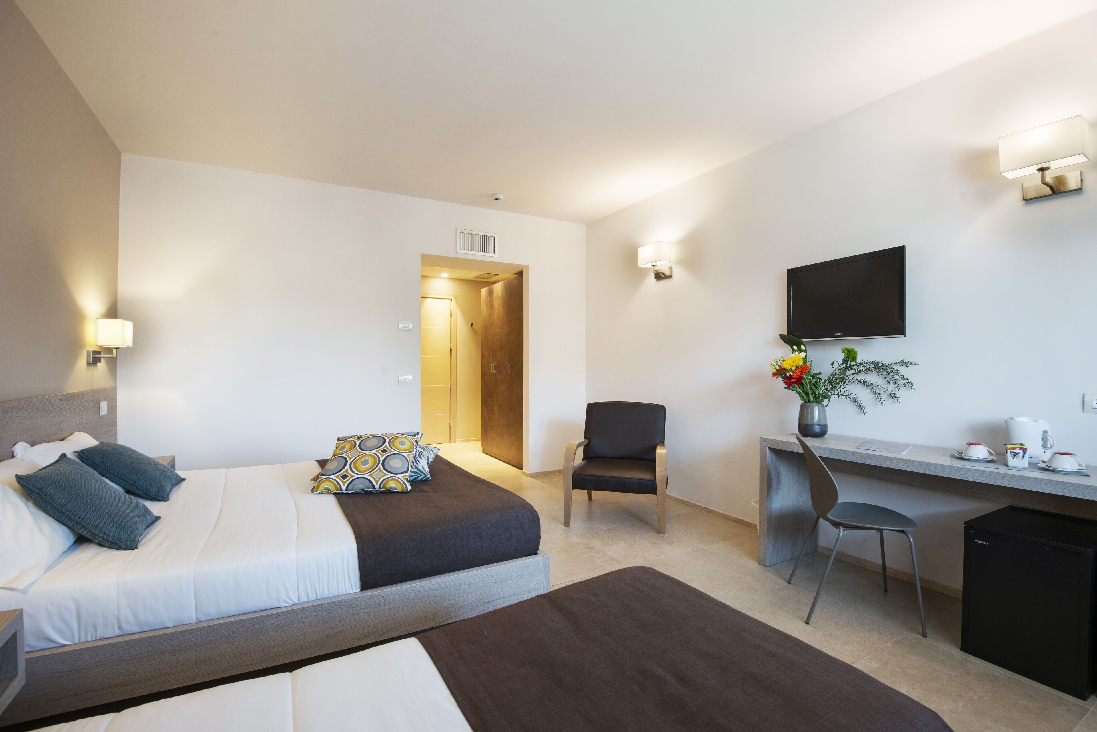 Een hotelkamer met een bed, een bureau, een stoel, een televisie en een kleine koelkast.